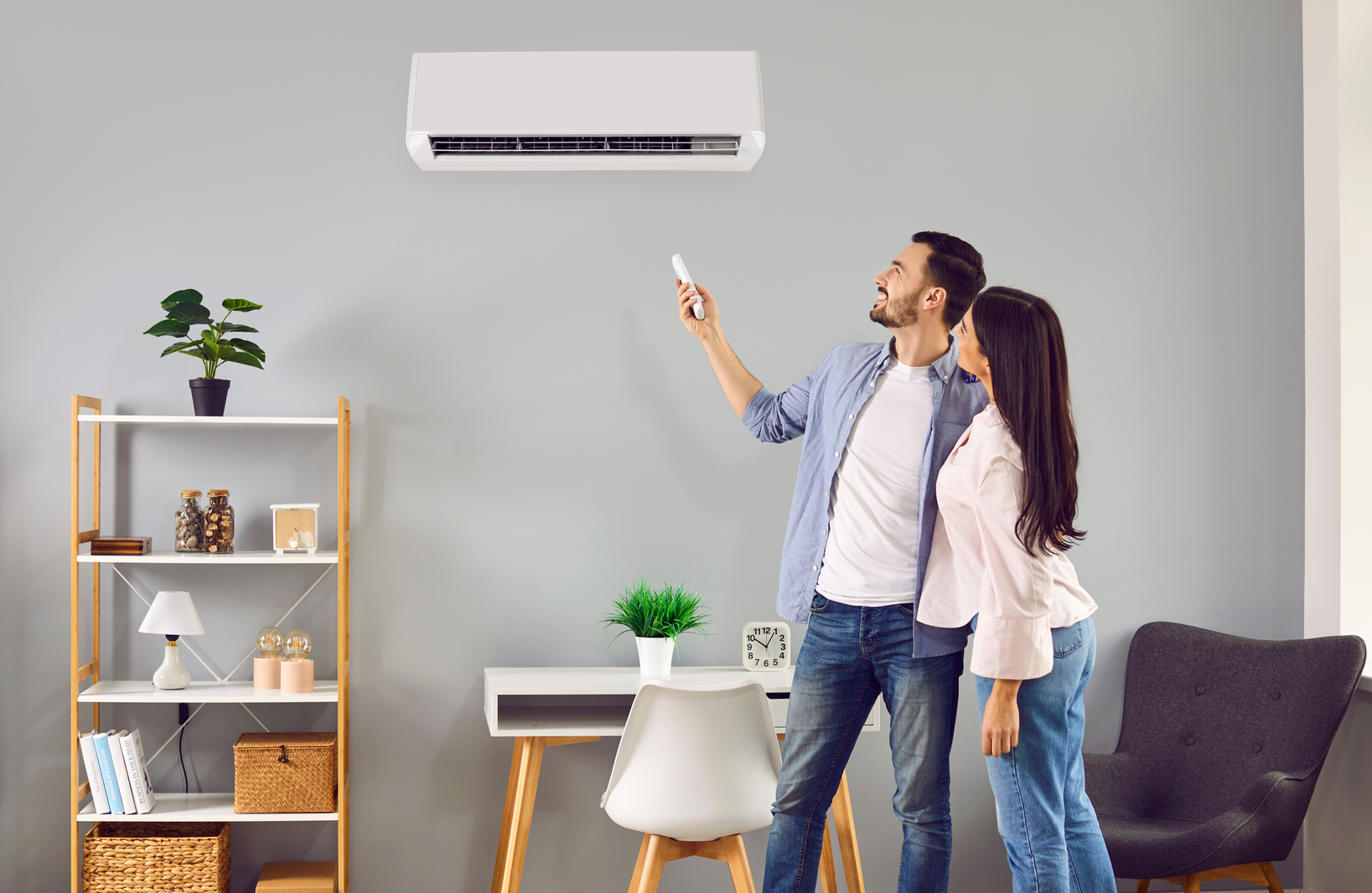 Young family couple using their modern air conditioning system with thermostat home